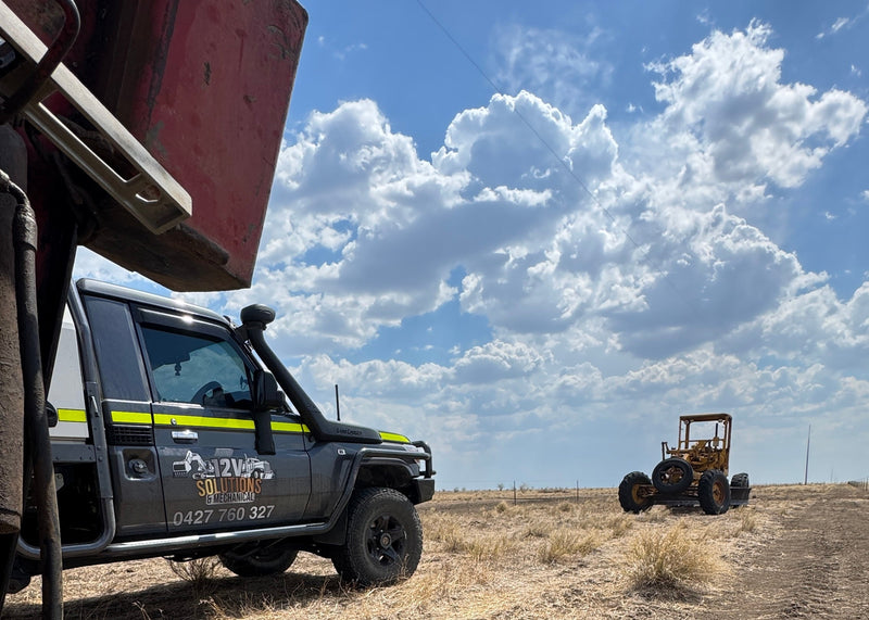 Off-road vehicle on a dirt road with a clear blue sky and clouds.