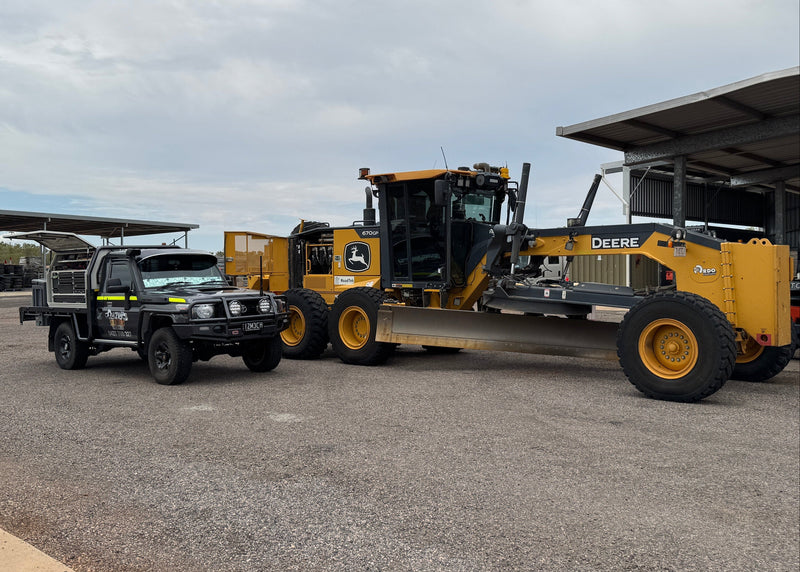 Large yellow construction vehicle on a paved area with a building in the background